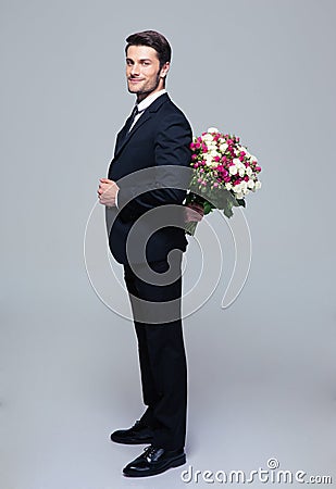 Businessman hiding bouquet of flowers behind his back Stock Photo