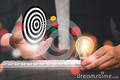 Businessman hold a darts aiming at the Bullseye is a target in black background - focus on Targeting the business. Business goal Stock Photo