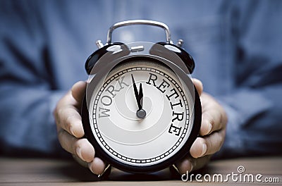 Businessman holding black alarm clock with clockwise countdown from work to retirement Stock Photo