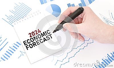 Businessman holding a black marker, notepad with text 2024 ECONOMIC FORECAST, business concept Stock Photo