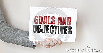 Businessman holding a card with text GOALS AND OBJECTIVES Stock Photo