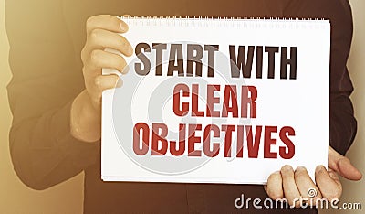 Businessman holding a card with text START WITH CLEAR OBJECTIVES Stock Photo