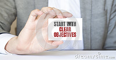 Businessman holding a card with text START WITH CLEAR OBJECTIVES Stock Photo