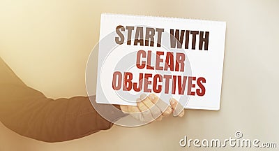 Businessman holding a card with text START WITH CLEAR OBJECTIVES Stock Photo