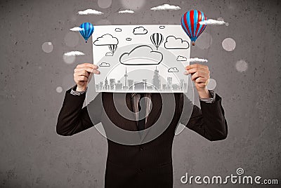 Businessman holding a cardboard with cityscape in front of his h Stock Photo