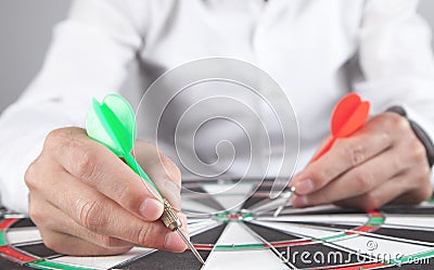 Businessman holding dart arrows in target dartboard Stock Photo