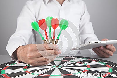 Businessman holding dart arrows in target dartboard Stock Photo