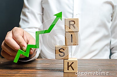 Businessman holding a green up arrow near the word Risk. Improving business resilience, reducing risks and costs. Development Stock Photo