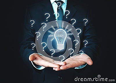 Businessman holding light bulb with question marks. Idea, Solution, Innovation Stock Photo