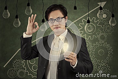 Businessman holding lightbulb with upward graph 2 Stock Photo