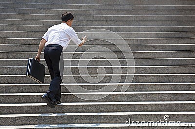 Businessman holding mobile and in hurry to run up on stairs Stock Photo