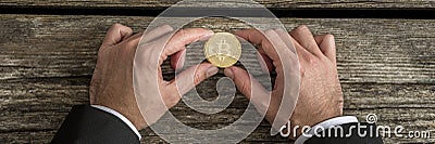 Businessman holding one golden Bitcoin in a wide cropped image Stock Photo