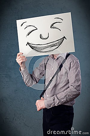 Businessman holding a paper with smiley face in front of his head Stock Photo