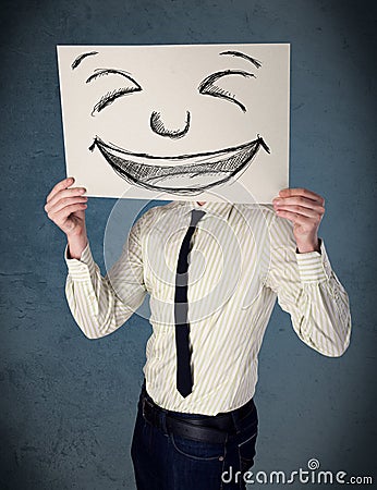 Businessman holding a paper with smiley face in front of his head Stock Photo