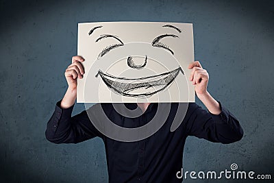 Businessman holding a paper with smiley face in front of his hea Stock Photo