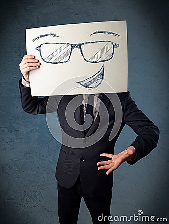 Businessman holding a paper with smiley face in front of his head Stock Photo