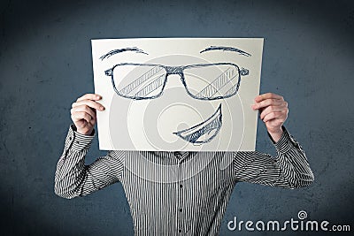 Businessman holding a paper with smiley face in front of his hea Stock Photo