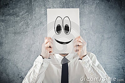 Businessman holding paper with smiley face in front of his head Stock Photo