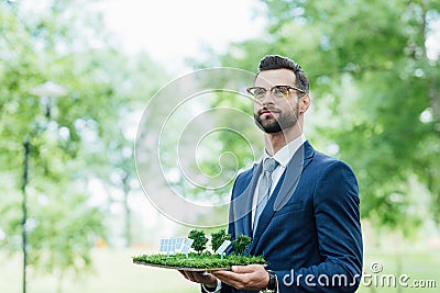 Businessman holding park layout with sun batteries and looking away while standing in park Stock Photo