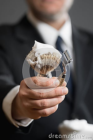 Businessman is holding Shaving Equipment in his Hands Stock Photo