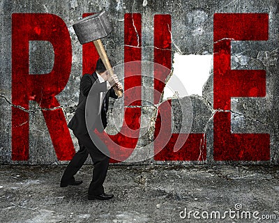 businessman holding sledgehammer hitting red rule word on concrete wall Stock Photo