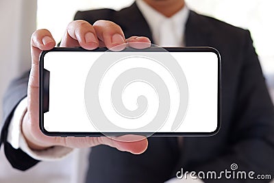 Businessman holding smartphone forward empty white screen for your text or picture. Stock Photo