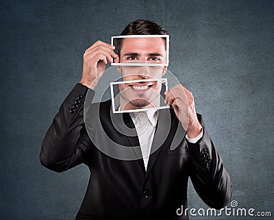 Businessman holding a smile over his face Stock Photo