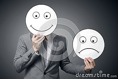 Businessman holding smile and sad mask. Conceptual image of a man changing his mood from bad to good Stock Photo