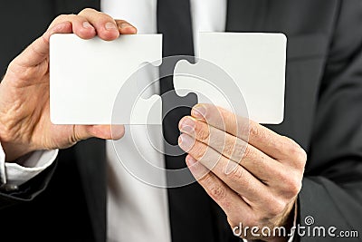 Businessman holding two pieces of a blank puzzle Stock Photo