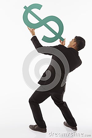 Businessman holding up a dollar sign, showing shooting gesture Stock Photo