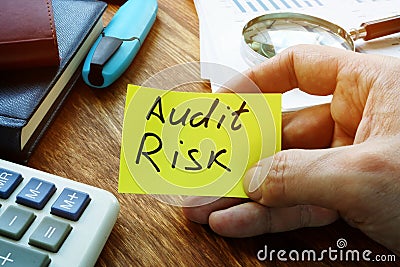 Businessman holds Audit Risk sign on a sheet Stock Photo