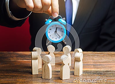 A businessman holds a blue clock over a team of workers. Time management concept. Deadline. Teamwork. Scrum. Human resources. Stock Photo