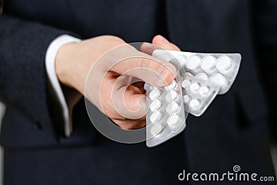 Businessman holds in hands a lot of white pills and packs of tab Stock Photo