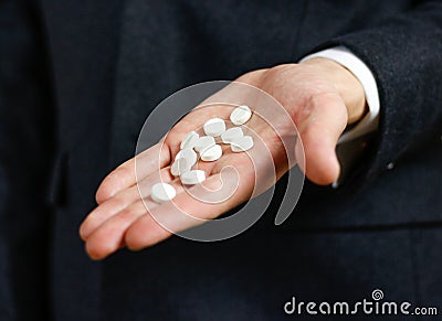 Businessman holds in hands a lot of white pills and packs of tablets Stock Photo