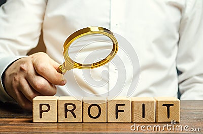 Businessman holds a magnifying glass over the word Profit. The concept of profitability and performance of business. Analysis of Stock Photo