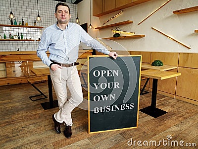 Businessman holds Open your own business sign Stock Photo