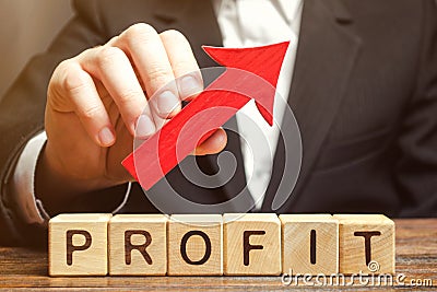 A businessman holds a red arrow up over wooden blocks with the word Profit. Successful business and high profits. Profitability. Stock Photo