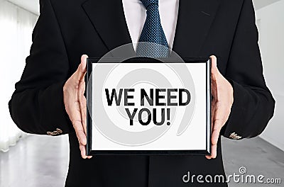 Businessman holds a signboard with the message we need you. Human resources recruitment or employment Stock Photo