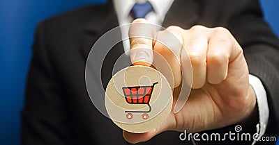 Businessman holds a wooden block with the image of a supermarket cart - shopping trolley. Retail and shopping. Ecommerce and Stock Photo