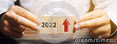 Businessman holds wooden blocks with the inscription 2022 and an up arrow. The forecast concept for 2022. Business forecasting. Stock Photo