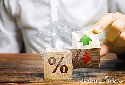 Businessman holds wooden blocks with percent and up or down arrow. Mortgage and loan rates. Interest rate, stocks, ranking. Stock Photo