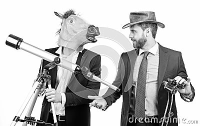 Businessman in horse head mask hold telescope and cowboy man with binoculars, business vision Stock Photo