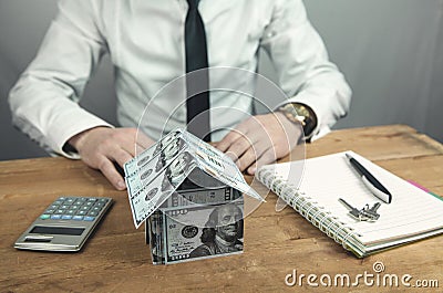 Businessman. House of dollars with keys and calculator on a wooden table Stock Photo