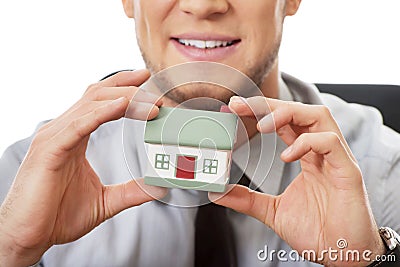 Businessman with house model by a desk. Stock Photo