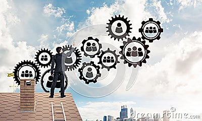 Businessman on house roof presenting teamwork and connection con Stock Photo