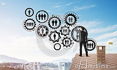 Businessman on house roof presenting teamwork and connection concept. Mixed media Stock Photo