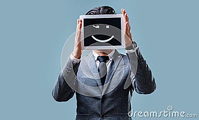 Businessman in jacket and tie holds a tablet computer with smile emoji Stock Photo
