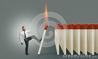 Businessman kicking a lit match to ignite a chain reaction Stock Photo