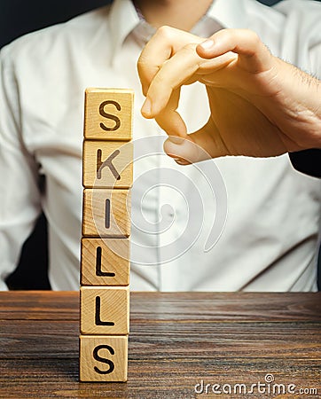 Businessman knocks down wooden blocks with the word Skills. The concept of the loss of skills. Suppression of talents. Business Stock Photo