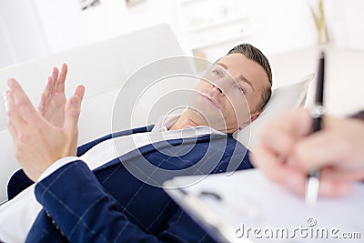 Businessman laying on couch talking to psychiatrist Stock Photo